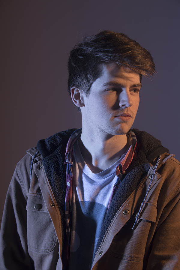 Austin Meros’s shoulders face forward with head turned to the right, lit dramatically, not smiling