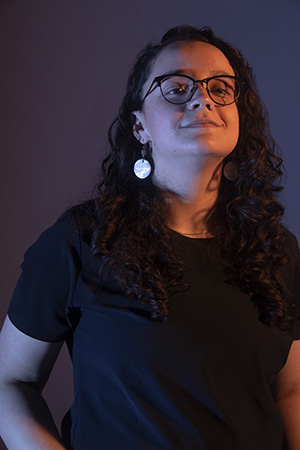 Kalila looks at camera with head tilted back, dramatic lighting, hands at hips