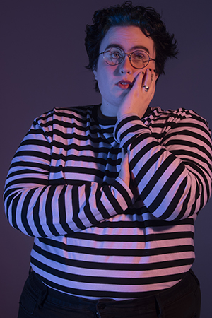 KD strands in dramatic lighting, arms crossed over chest, with left hand resting on cheek